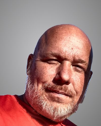 Chris Naylon, smiling, in a red shirt.